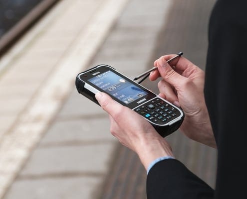 handheld nautiz e-ticket pro ii in front of railway